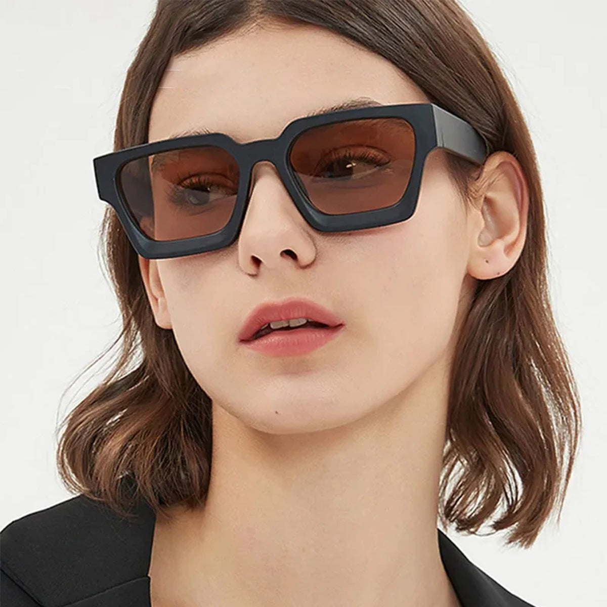 Model wearing black chunky square sunglasses with brown tinted lenses