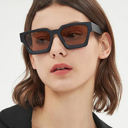 Model wearing black chunky square sunglasses with brown tinted lenses