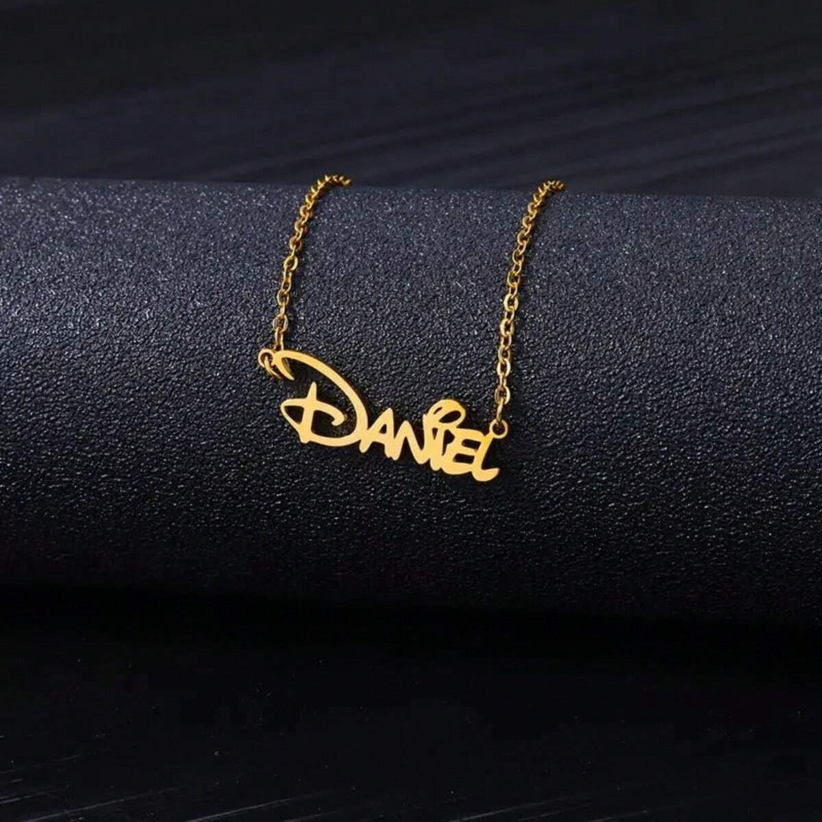 Name necklace draped on a dark surface