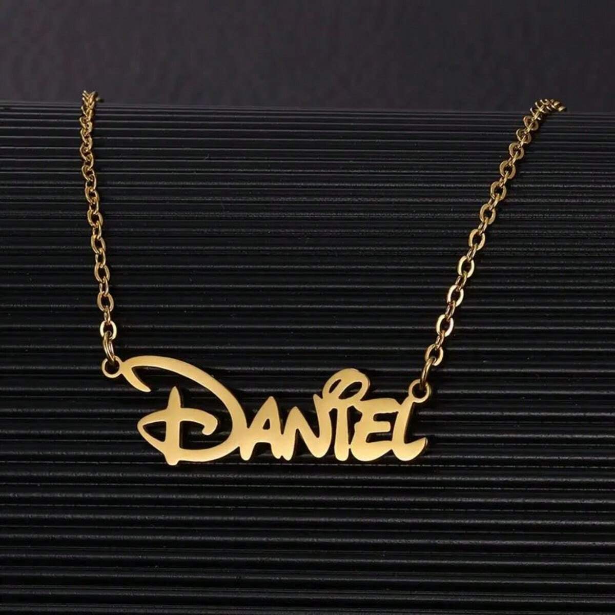 Gold personalized name necklace on a dark background