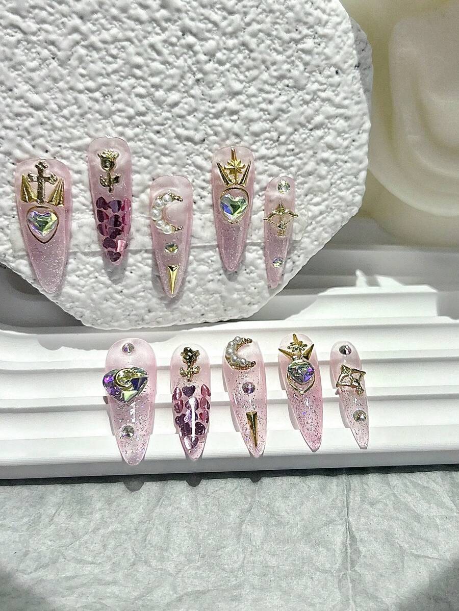 Love Spell press-on nail set laid out, aurora heart crystals and gold star charms