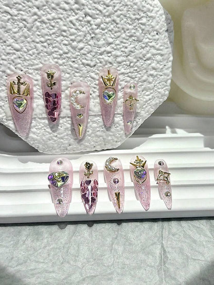 Love Spell press-on nail set laid out, aurora heart crystals and gold star charms