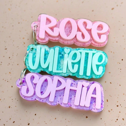 Layered acrylic personalized name keychains in pink, teal and purple glitter