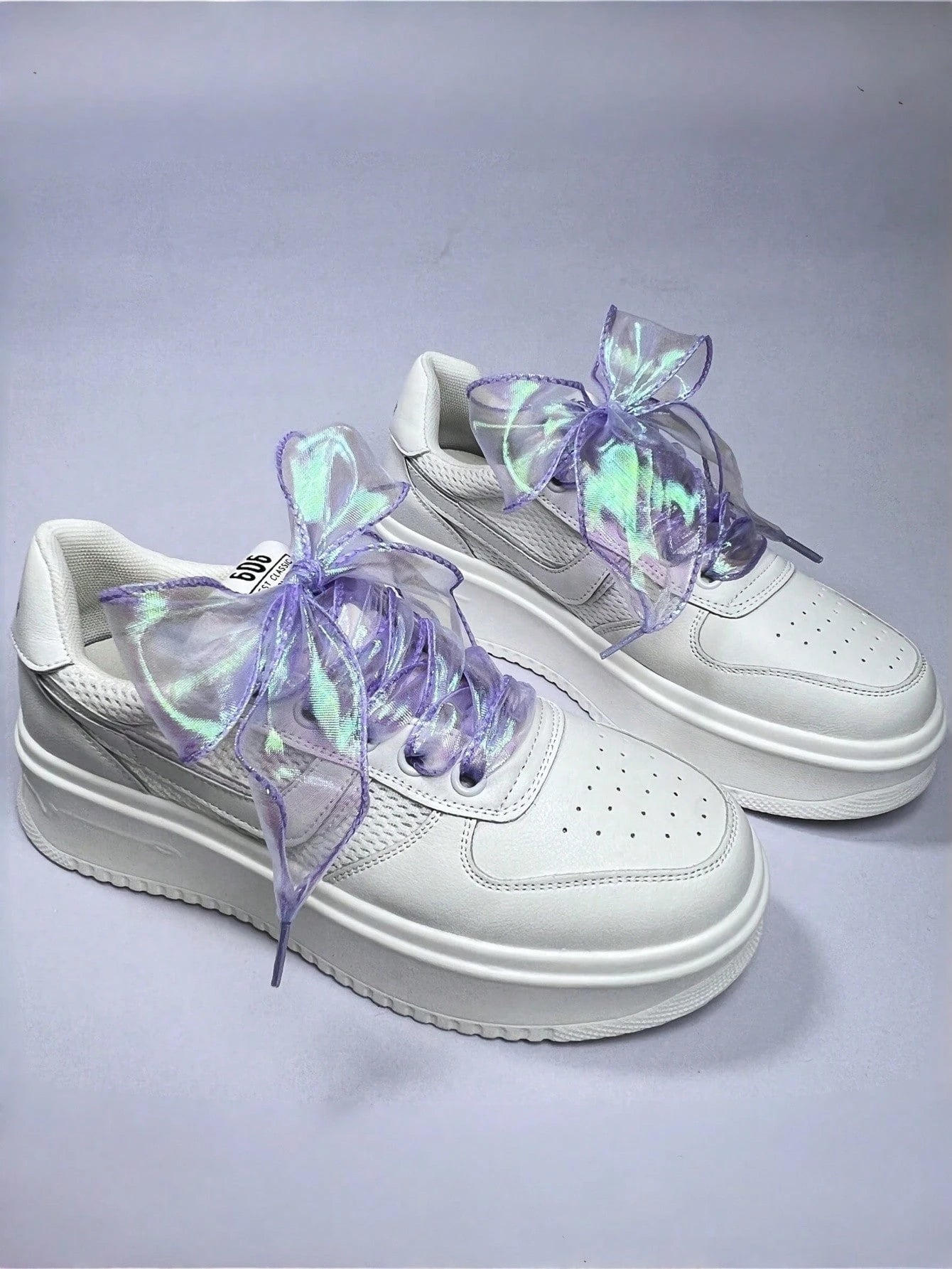 Iridescent lilac ribbon shoelaces tied on white sneakers