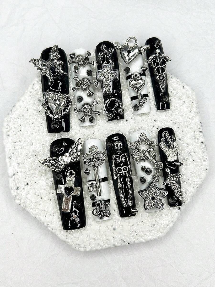 Close detail of the rhinestone cross and skull charms on the black nails