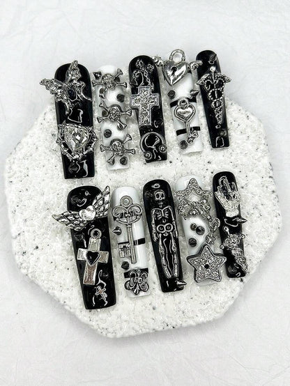 Close detail of the rhinestone cross and skull charms on the black nails