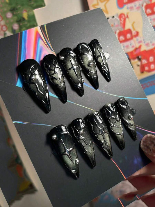 Long stiletto press-on nails in high gloss black with raised liquid chrome swirls