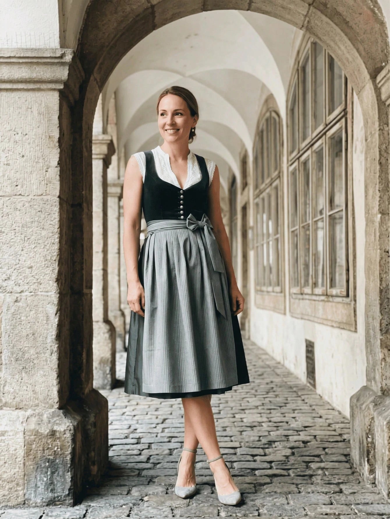 Model wearing the Prost Darling lace-trim dirndl dress under a stone archway