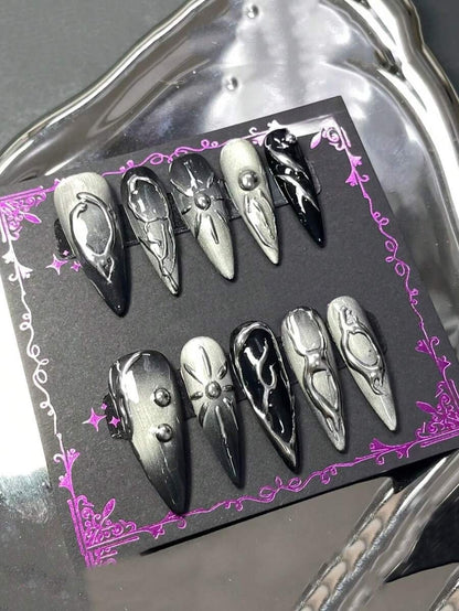 Chrome silver and black stiletto press-on nails on a dark card