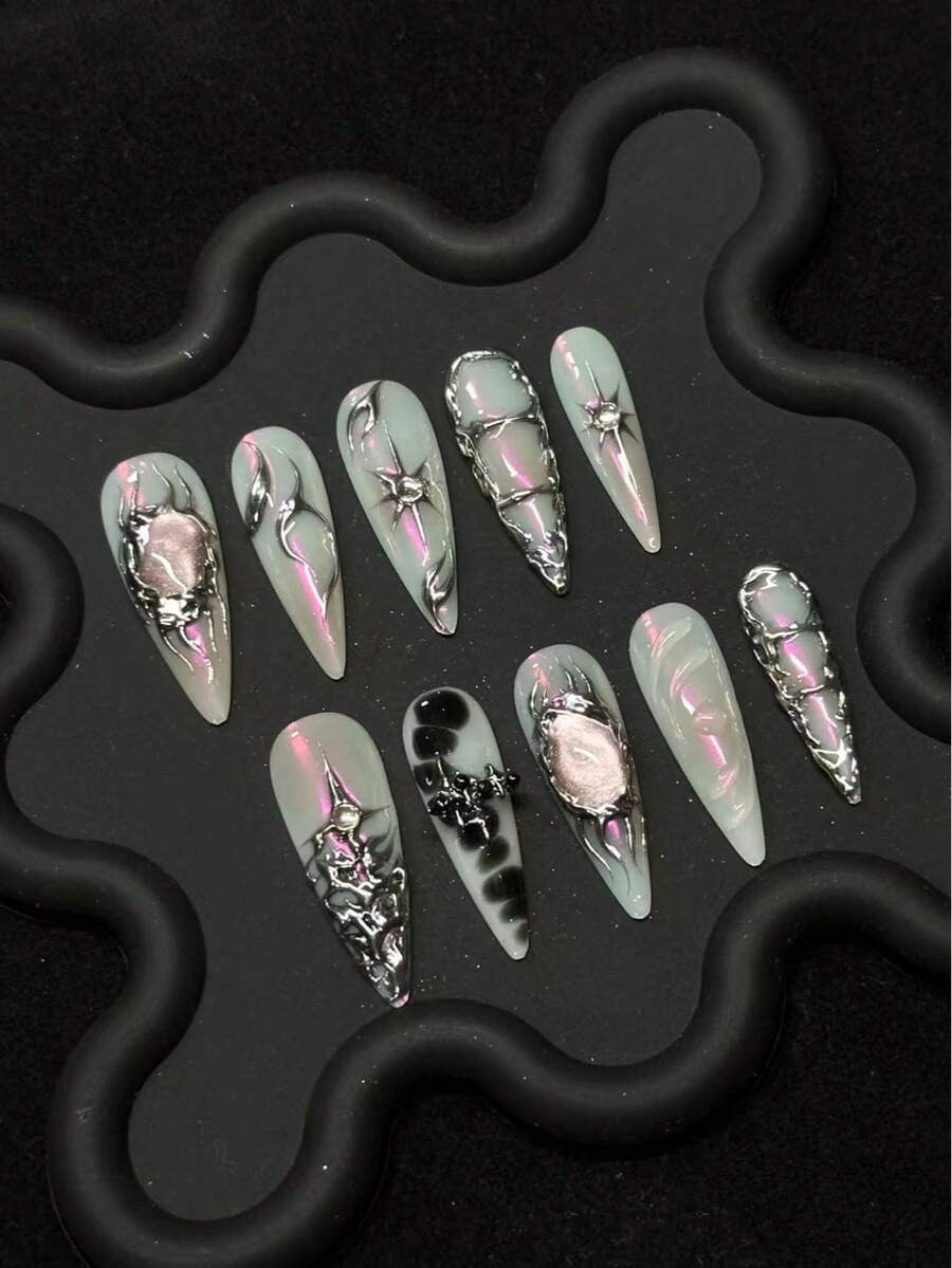 Mint and pink iridescent stiletto press-on nails with raised silver detail on a black tray