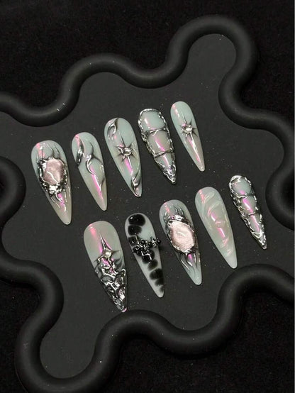 Mint and pink iridescent stiletto press-on nails with raised silver detail on a black tray