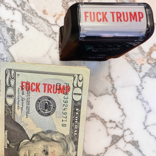 Fuck Trump self-inking rubber stamp with red ink displayed on a $20 bill against a marble background - anti-Trump political protest stamp