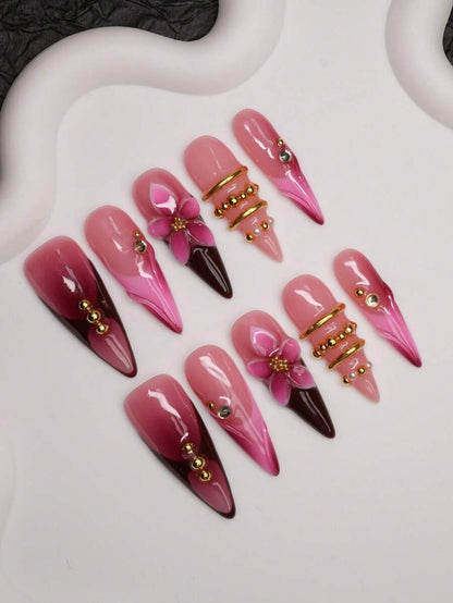 Burgundy and hot pink stiletto press-on nails with gold beads shown at an angle