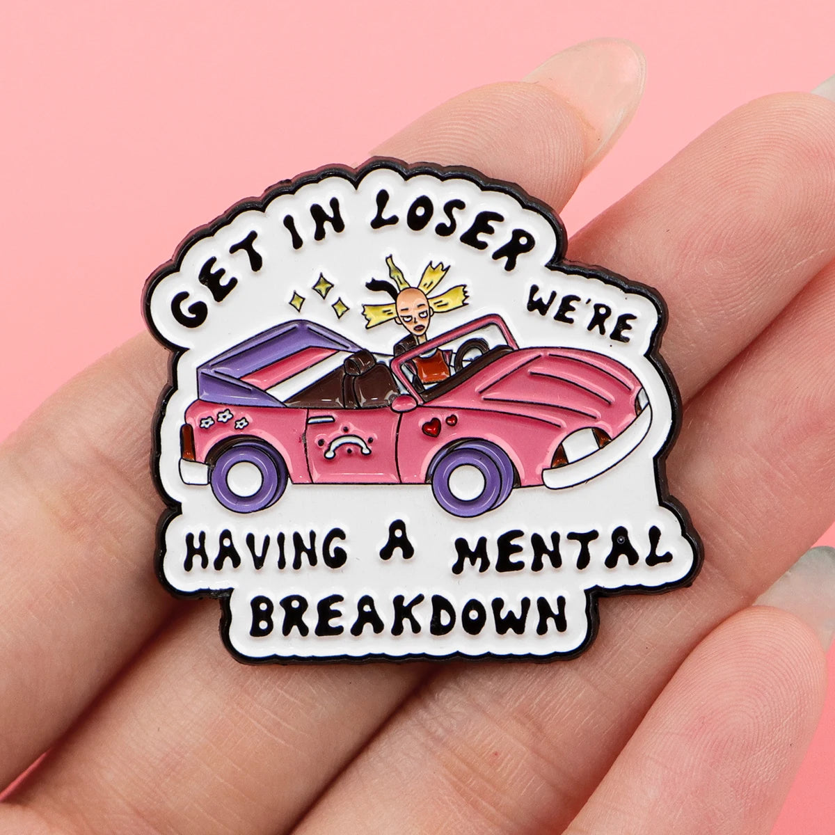 Enamel pin held in hand for scale