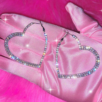 Silver tone crystal heart hoop earrings on pink silk