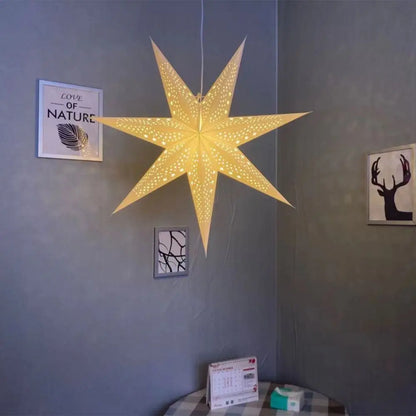 Lodestar folding paper star lantern lit and hanging on a wall