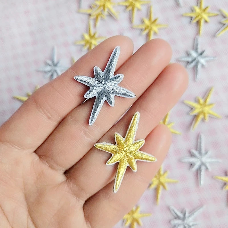 Silver and gold star patches held in a hand for scale