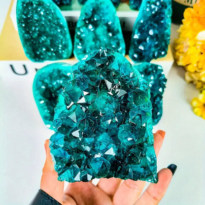 Aura crystal cluster held in a hand for scale