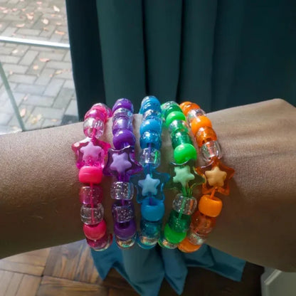 Stacked rainbow star kandi bracelets on forearm