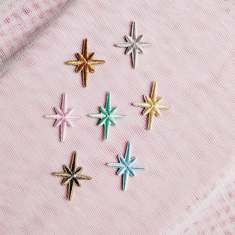 Metallic embroidered eight-point star patches arranged on pink tulle