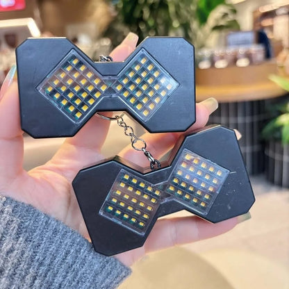 Two black LED hourglass keychains lit up