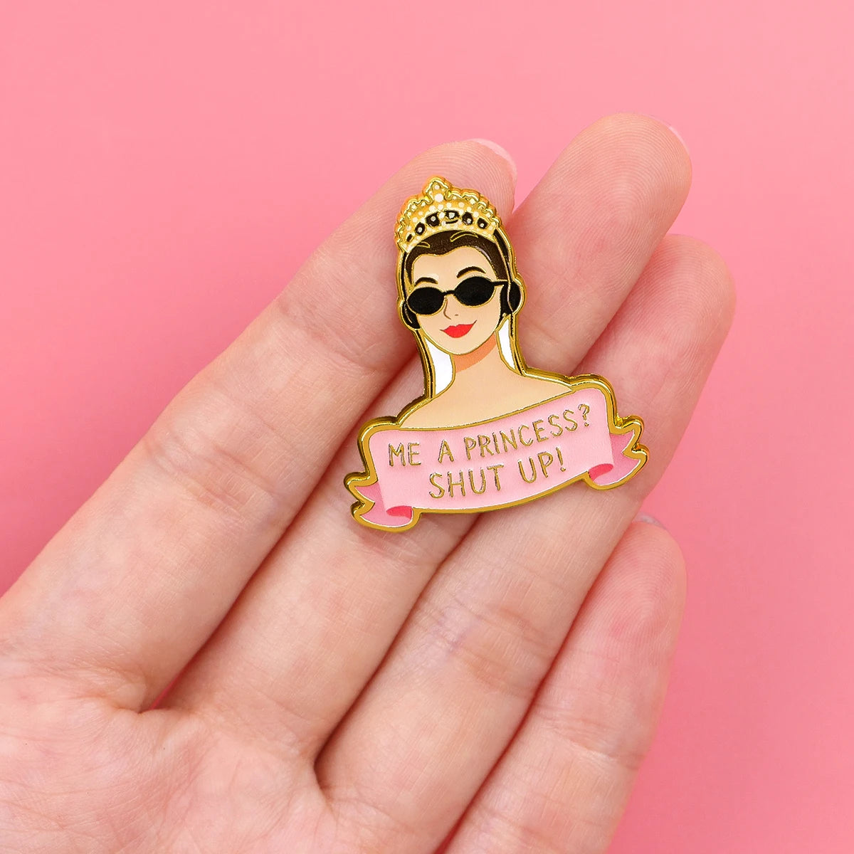 Enamel pin held in hand for scale