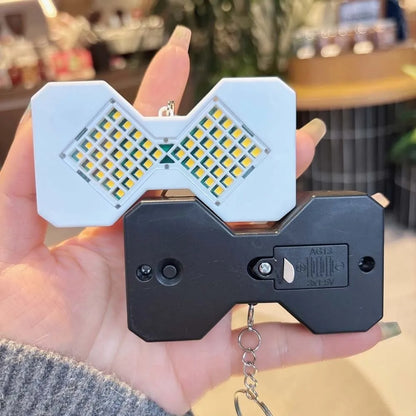 White and black LED hourglass keychains held in hand showing front and back