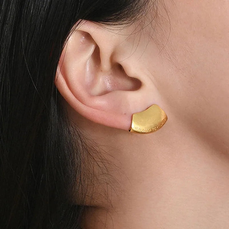 Brushed gold sculptural stud worn on ear