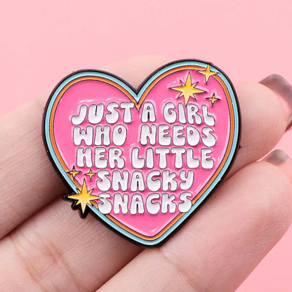 Snacky Snacks heart enamel pin held in hand for scale