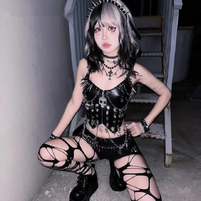 Model crouching in the spiked skull chain corset top with a mini skirt and boots
