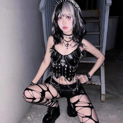 Model crouching in the spiked skull chain corset top with a mini skirt and boots