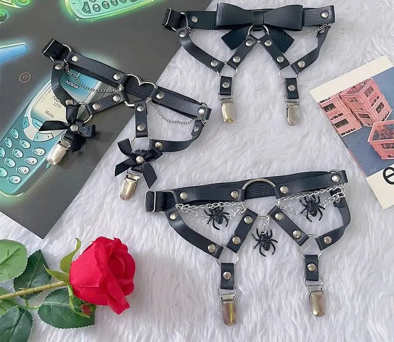 Flat lay of two chained thigh garters with a red rose