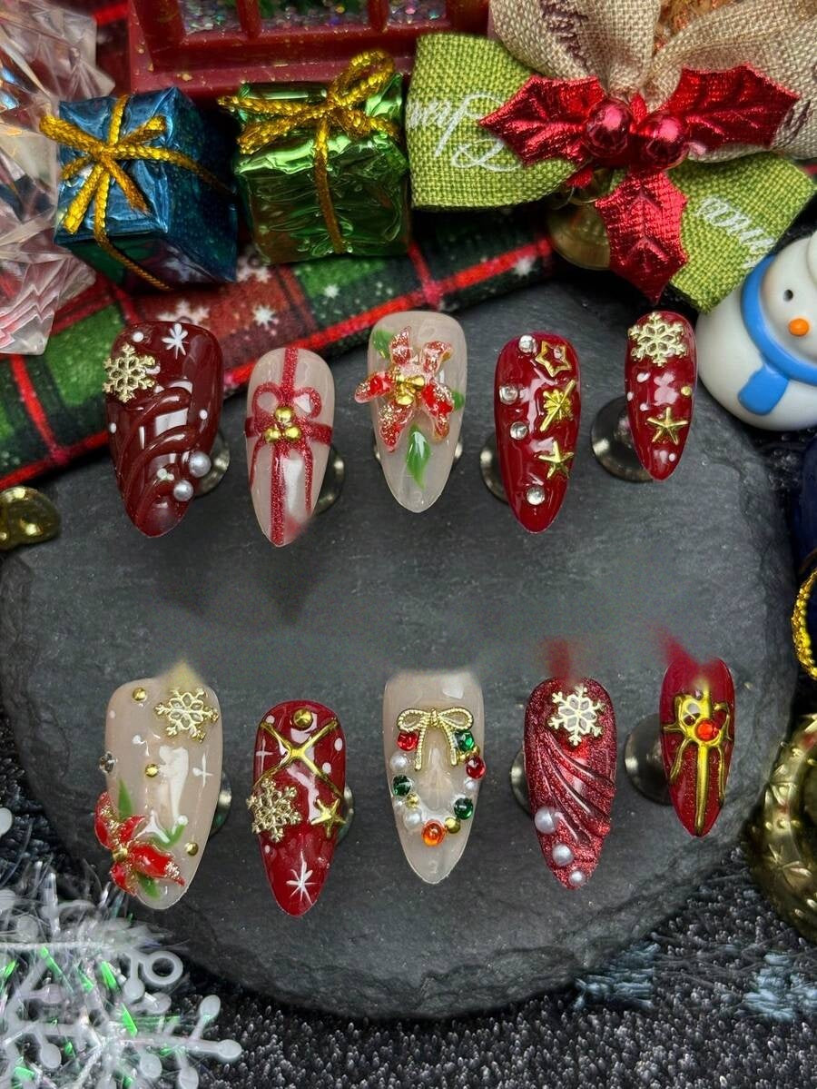 Red and nude almond press-on nails with 3D poinsettias, gold bows and pearls