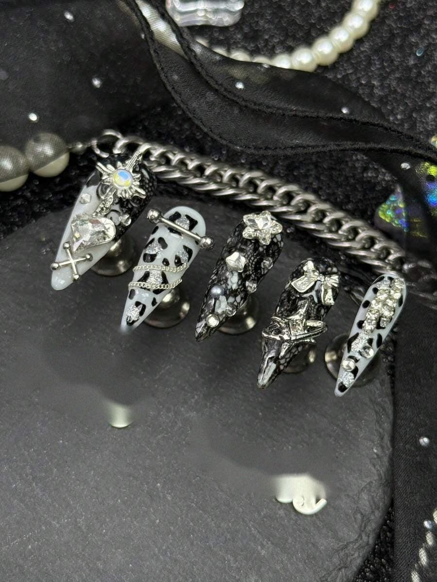 Long stiletto press-on nails in black and white cow print with silver crosses and crystals