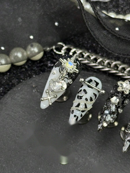 Close detail of the silver star charm and draped chain on the cow print nails