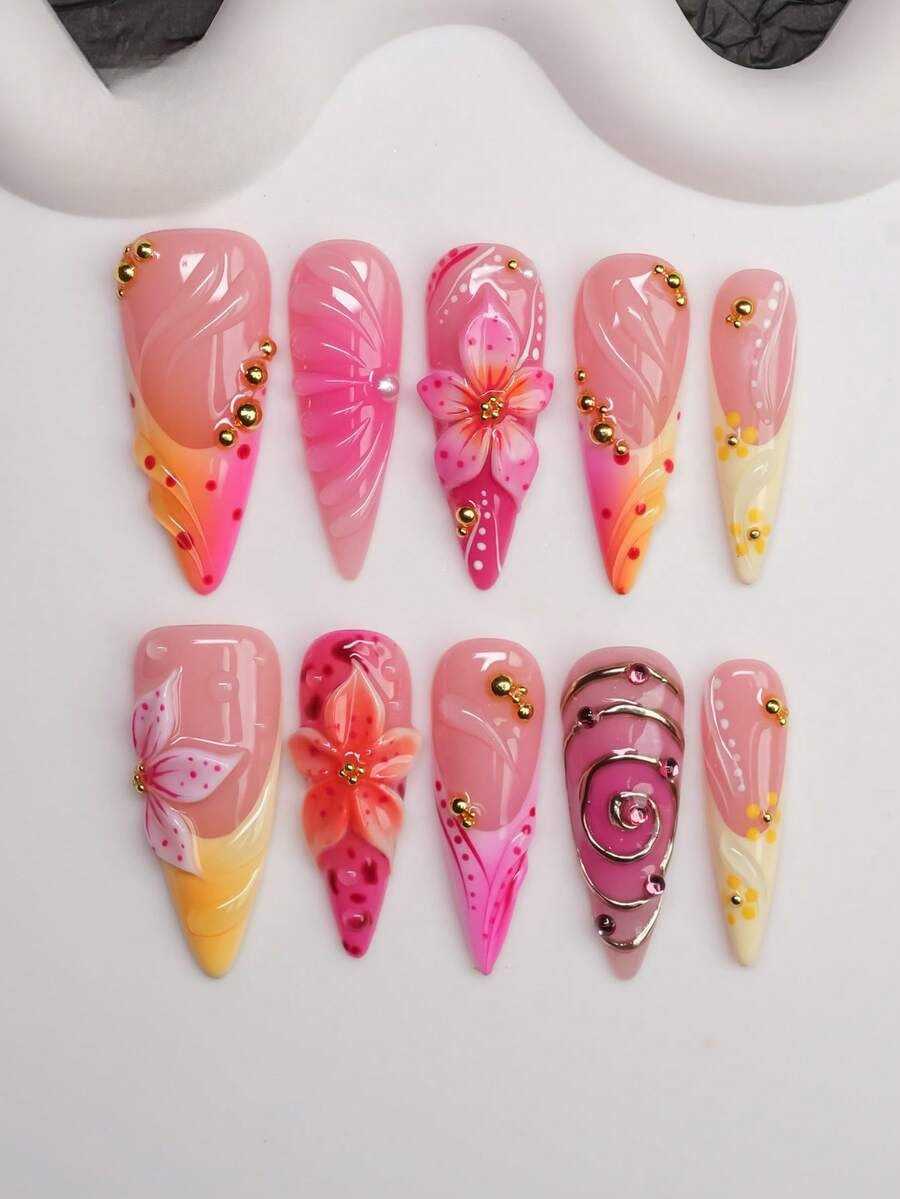 Long almond press-on nails in a peach, pink and yellow sunset fade with 3D lilies and gold beads