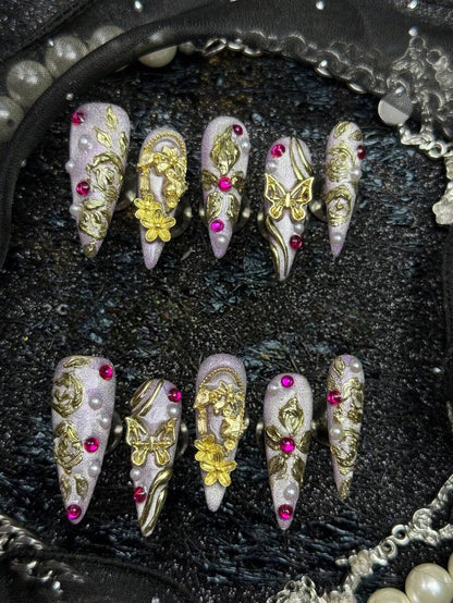 Long stiletto press-on nails in lilac cat-eye with 3D gold roses, butterflies and pink crystals