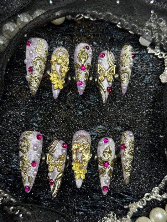 Long stiletto press-on nails in lilac cat-eye with 3D gold roses, butterflies and pink crystals