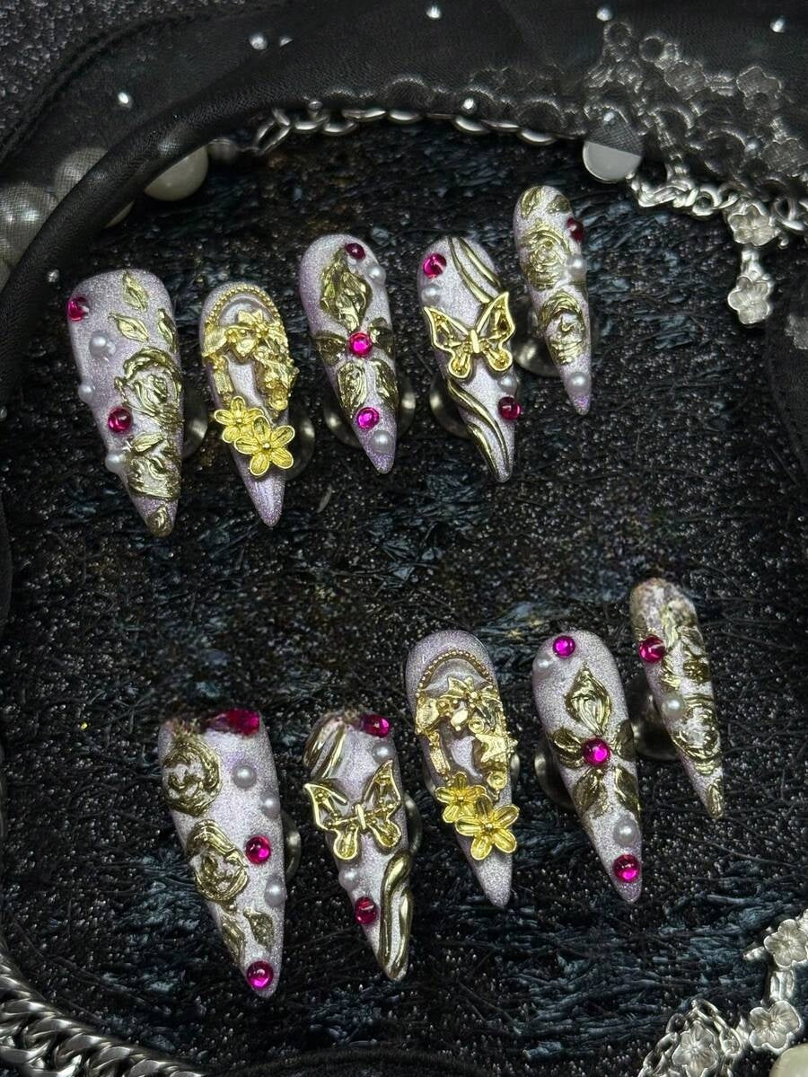 Full set of lilac and gold butterfly press-on nails laid out by finger
