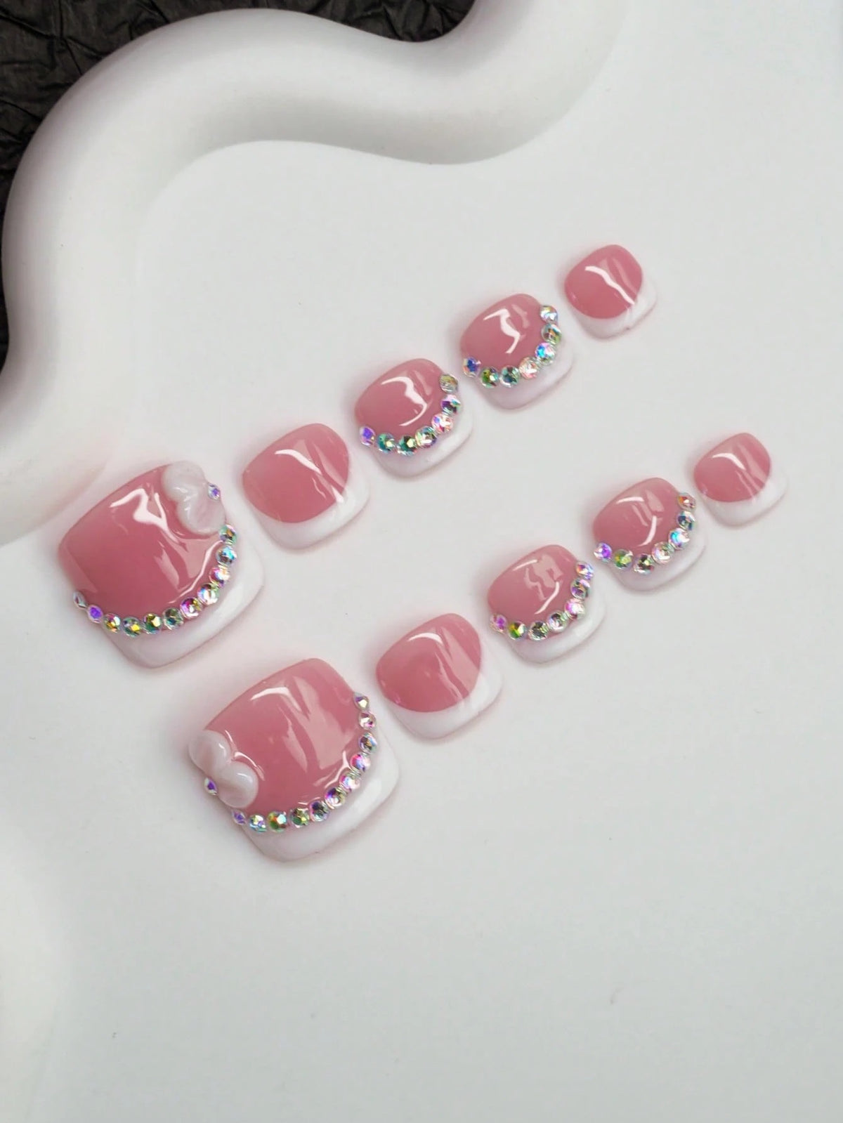 Pink French press-on toenails with crystal tips at an angle