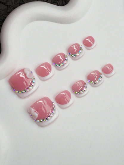 Pink French press-on toenails with crystal tips at an angle