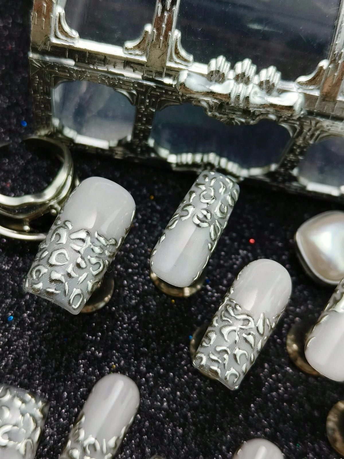 Close-up of sculpted silver relief on square nails