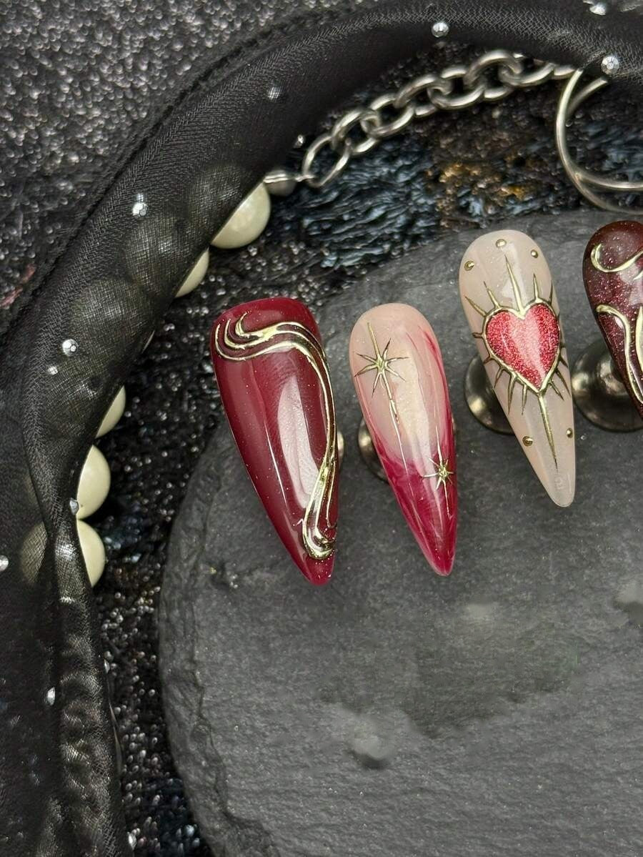 Bleeding Heart stiletto nails close up with gold thorn linework